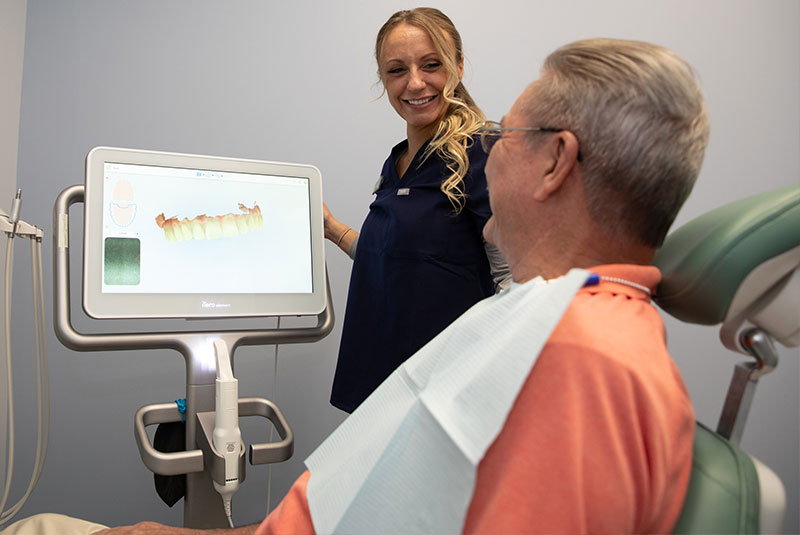 staff member presenting dental procedure images for patient inside of dental practice