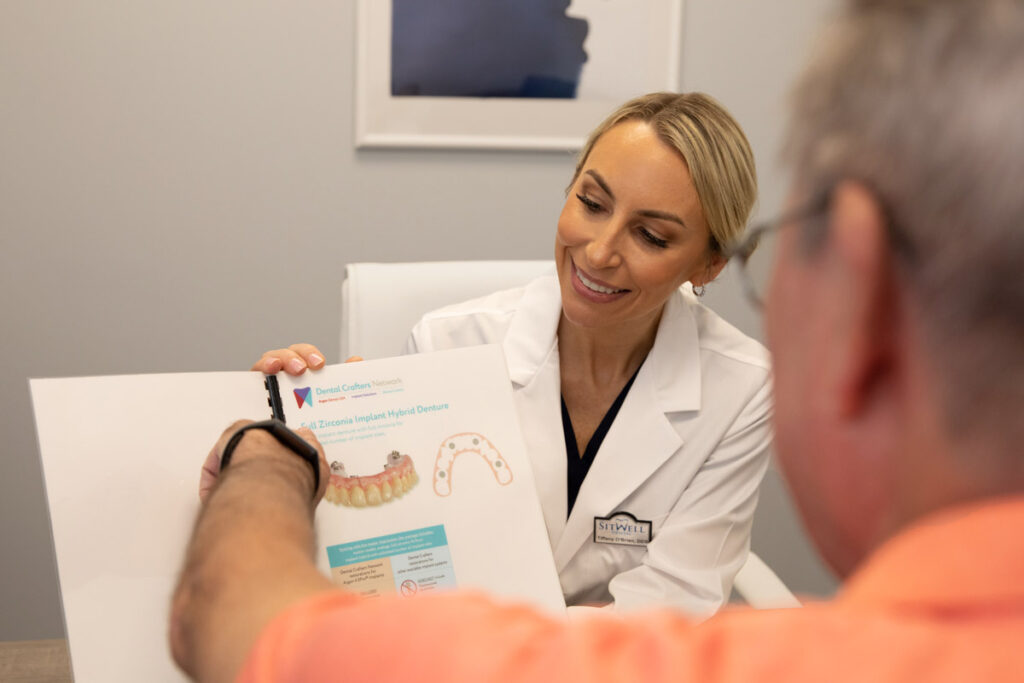 Dr Tiffany O'Brien Showing A Dental Patient A Dental Implant Pamphlet